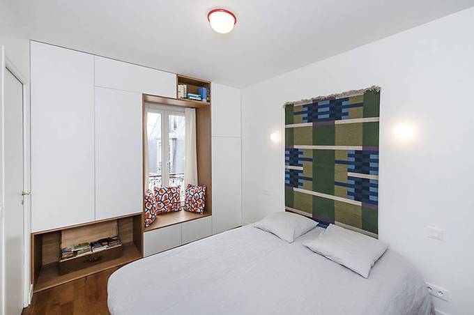 Phòng ngủ tối giản với một vài ngăn tủ mở và điểm nhấn từ gối dựa, thảm treo đầu giường Phòng ngủ tối giản