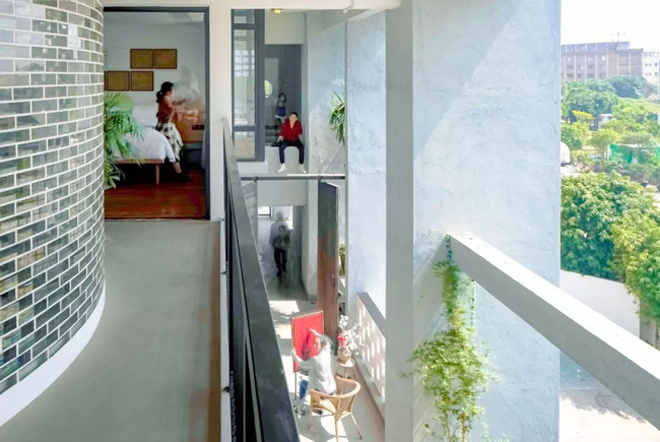 Ảnh chụp dọc theo hành lang ngôi nhà, phía trên bên trái là một phụ nữ đang lau dọn, ở dưới là một người đang ngồi vẽ tranh, một người đang đi bộ ở hành lang, phía trên có hai người một ngồi một đứng thiết kế nhà đẹp