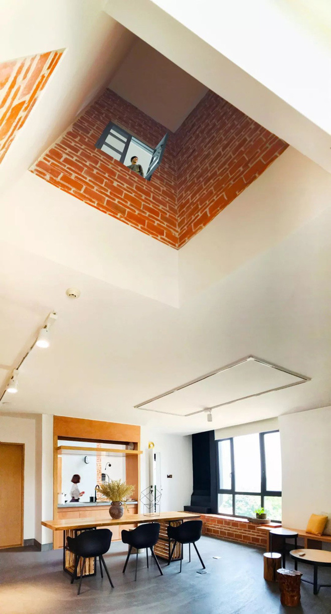 Không gian sinh hoạt chung gồm một bộ bàn tròn và một bộ bàn dài, bên phải là khung cửa sổ kính, ở giữa là căn bếp nhỏ nhà độc đáo