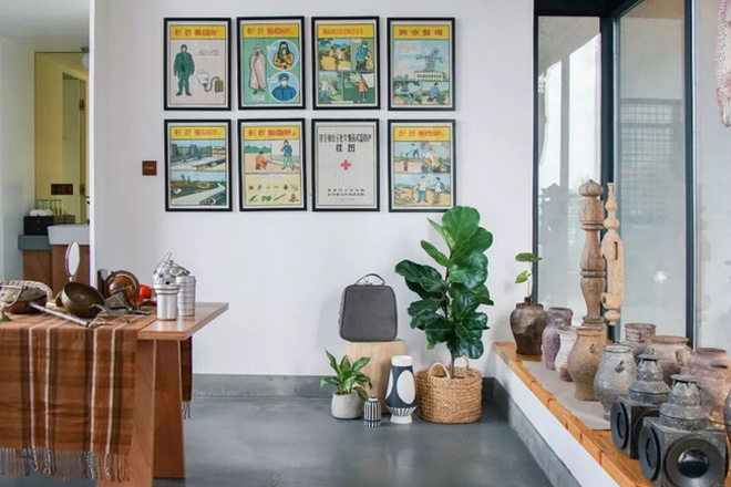 Căn phòng một bên là bàn để đồ, một bên là những bình gốm xếp ngay ngắn dưới khung cửa kính, chính giữa là bức tường có treo các bức tranh vẽ góc trưng bày đồ gốm