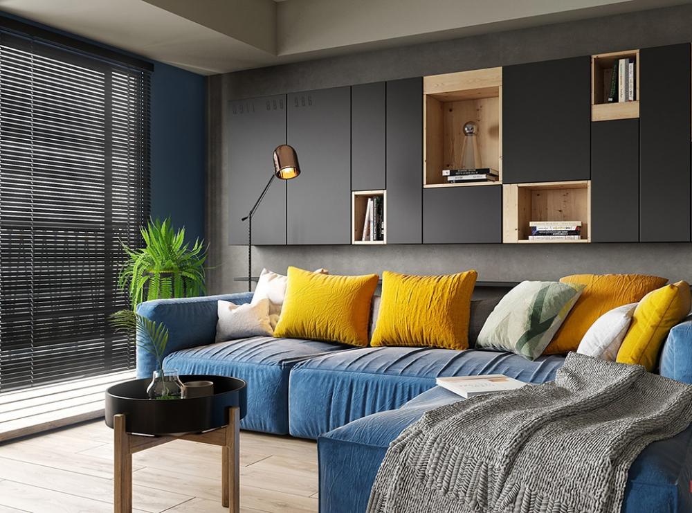 Ghế sofa bọc vải màu xanh dương, bên trên là gối dựa màu vàng tươi, bức tường sau sofa sơn màu xám sofa màu xanh dương
