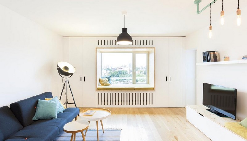 Phòng khách bố trí cạnh khung cửa sổ, các món nội thất đều có kích thước nhỏ nhắn. Sofa đơn màu xanh hải quân kết hợp bàn trà và thảm trải sàn giúp căn phòng có điểm nhấn. phòng khách cạnh khung cửa sổ