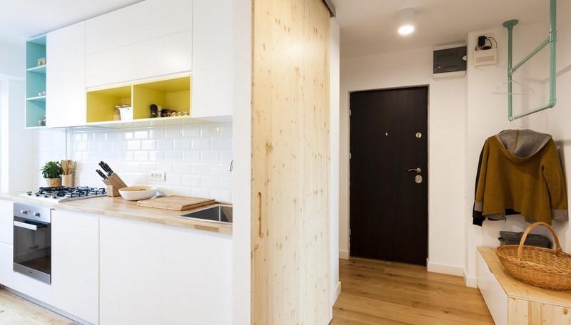 Bên trái là khu bếp, bên phải là lối vào căn hộ có giá treo quần áo và kệ giày trang trí lối vào căn hộ