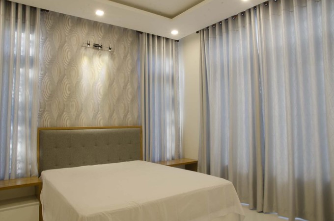 Ảnh chụp phòng ngủ của bố mẹ được thiết kế theo phong cách tối giản với giường gỗ, ga trắng và hệ thống rèm dày, giúp cản nắng và đảm bảo sự riêng tư khi cần thiết thiết kế không gian nhà phố đẹp