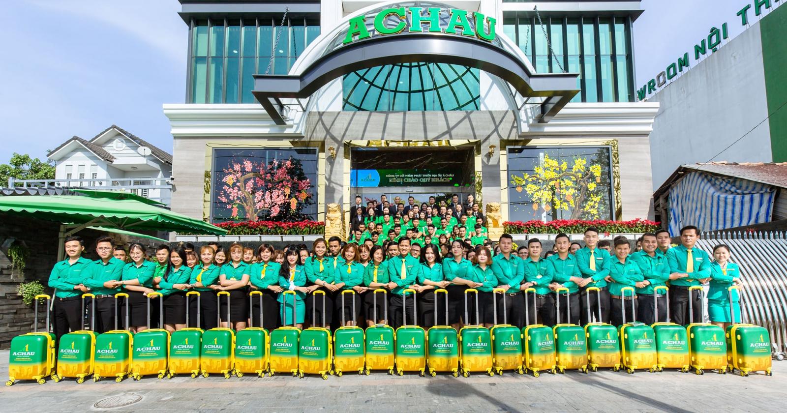 nhiều người mặc áo xanh đứng chụp ảnh trước toà nhà